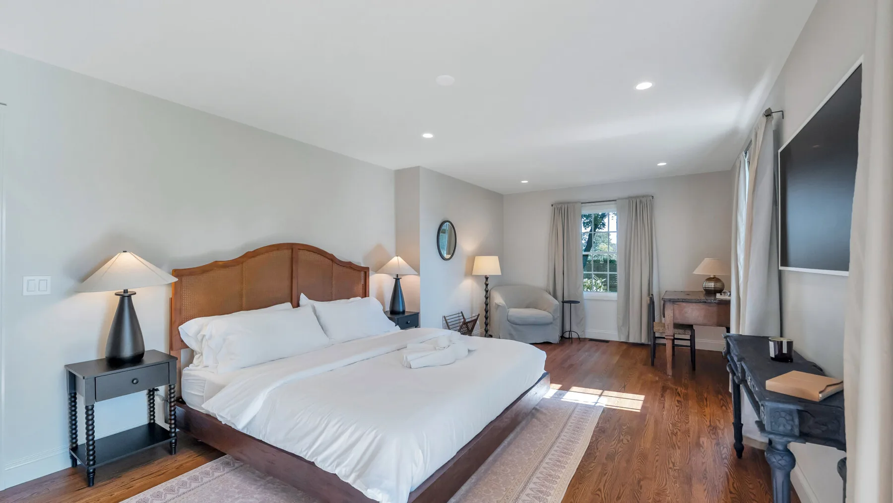A bright bedroom with a large bed and a sitting area by the window.