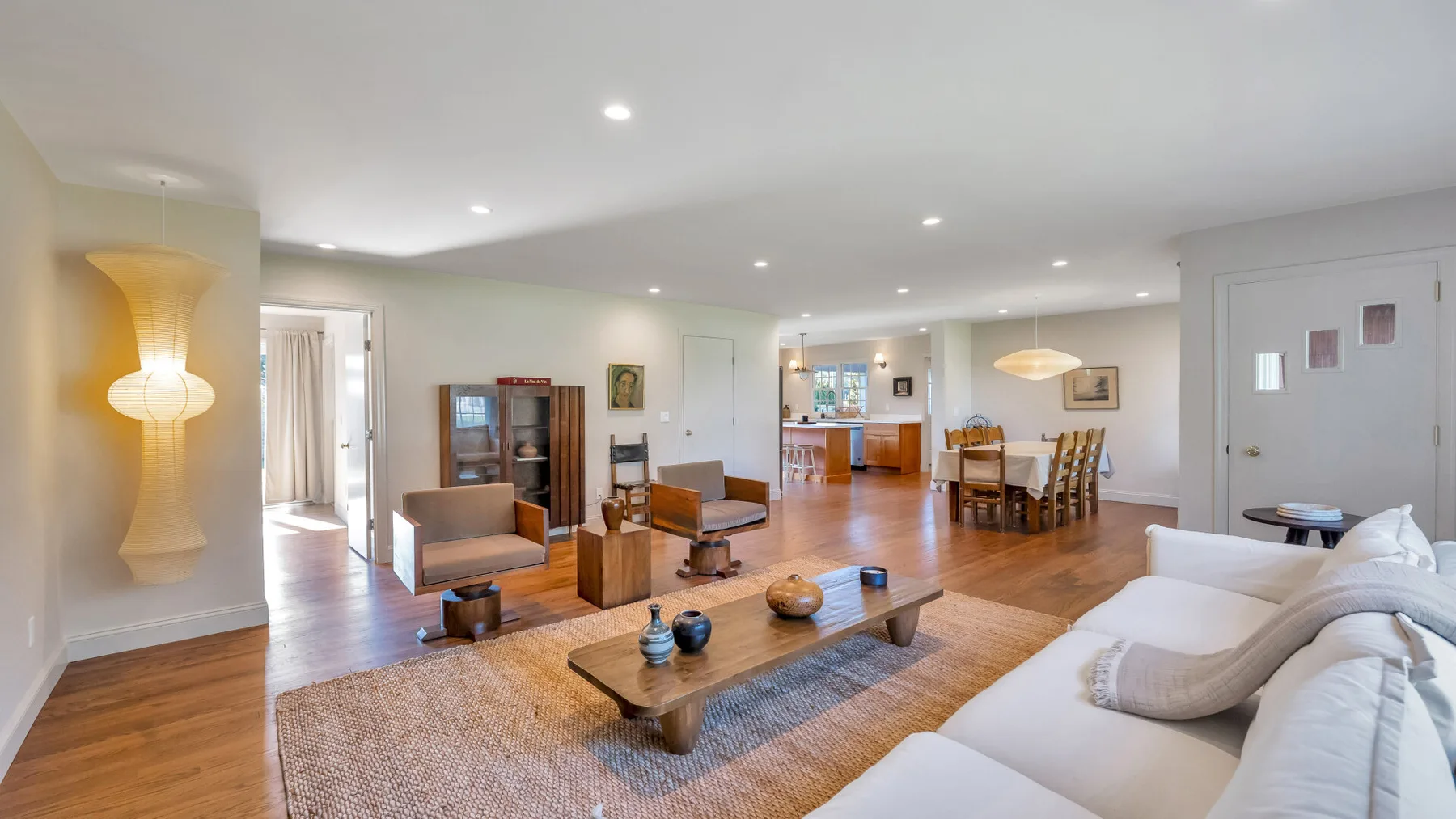 A bright living room with seating around a low coffee table and an open kitchen beyond.