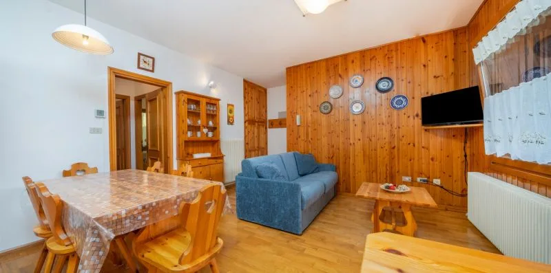 A living and dining room with blue seating and a wooden dining table.