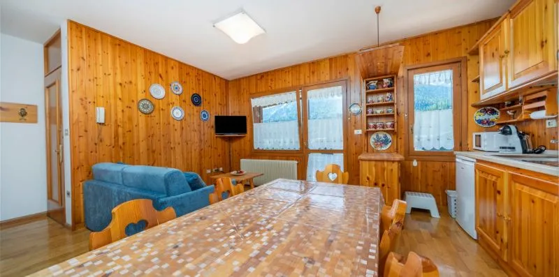 A wood-paneled dining area with a long table, seating, and windows.