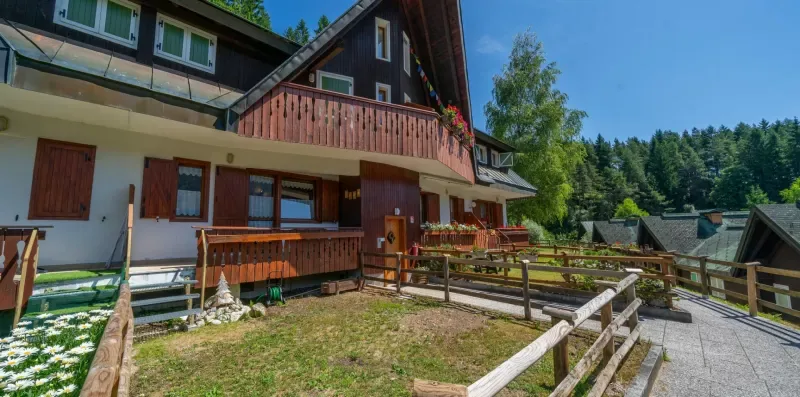 A chalet-style building with wooden balconies stands beside a gravel driveway.