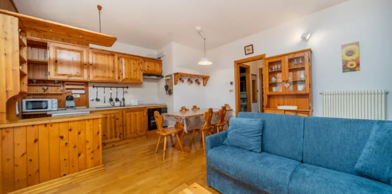 A living and dining area with a blue sofa and a wooden kitchen.