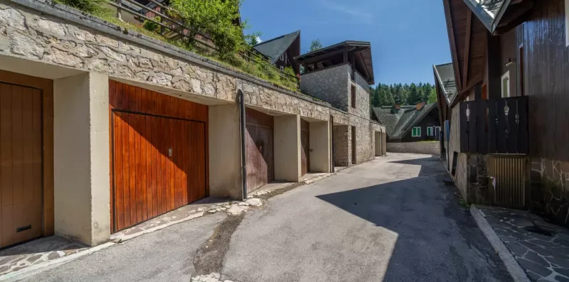 An outdoor lane runs past a row of garage doors and buildings.