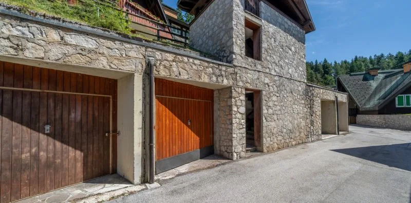 A stone building with wooden garage doors beside a paved driveway.