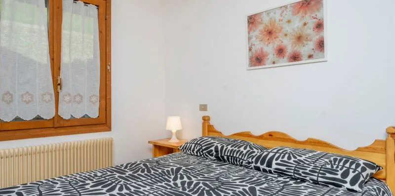A bedroom with a bed dressed in black-and-white patterned bedding.