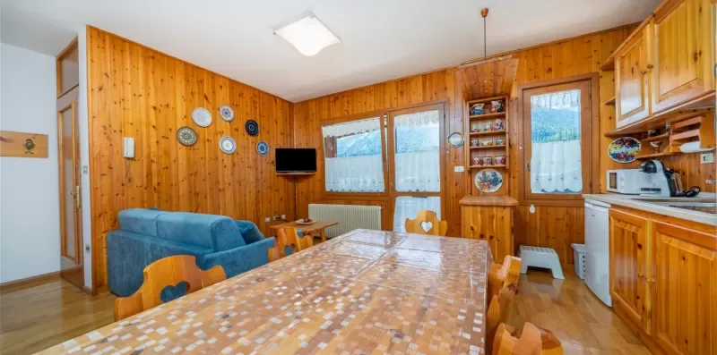 A wood-paneled dining and kitchen area with a long table and blue seating.