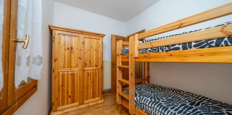 A bedroom with wooden bunk beds and a wardrobe.