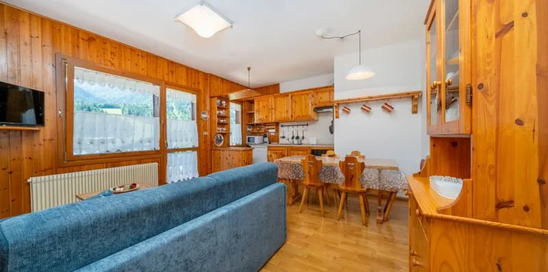 A wood-paneled living and dining area with a blue sofa and a table.