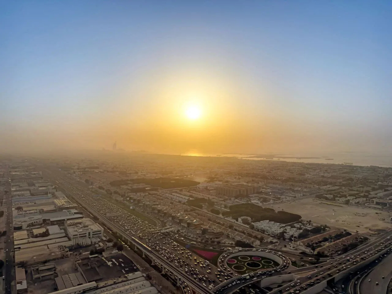 Vista aérea de una ciudad extensa al atardecer, con carreteras y edificios en primer plano.