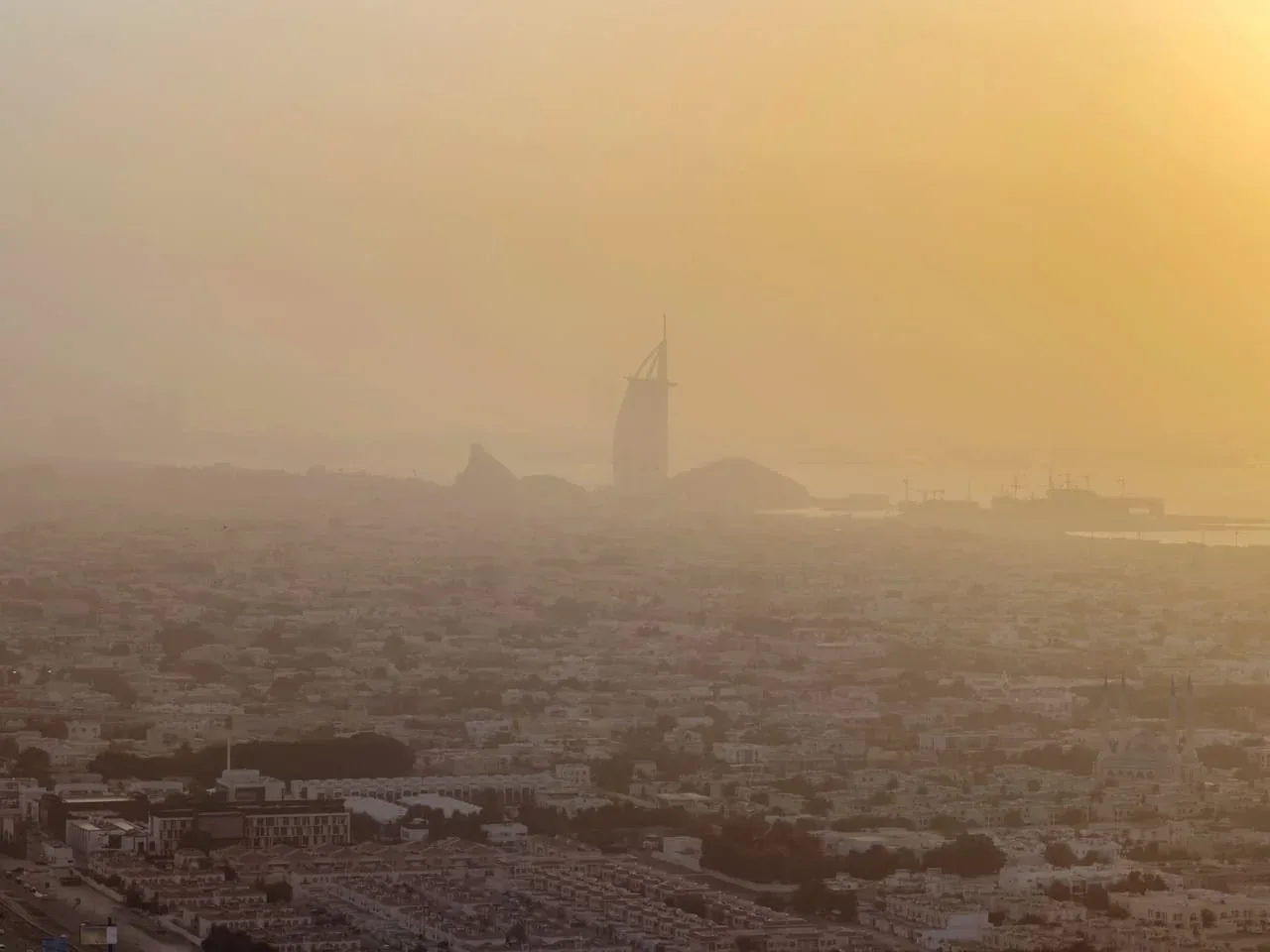 Un horizonte urbano brumoso se extiende bajo un cielo dorado.