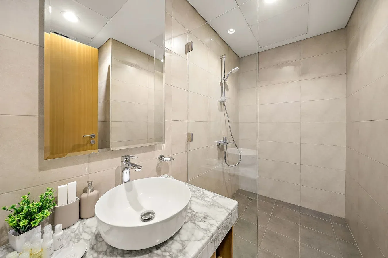Un baño alicatado con lavabo y una ducha montada en la pared.
