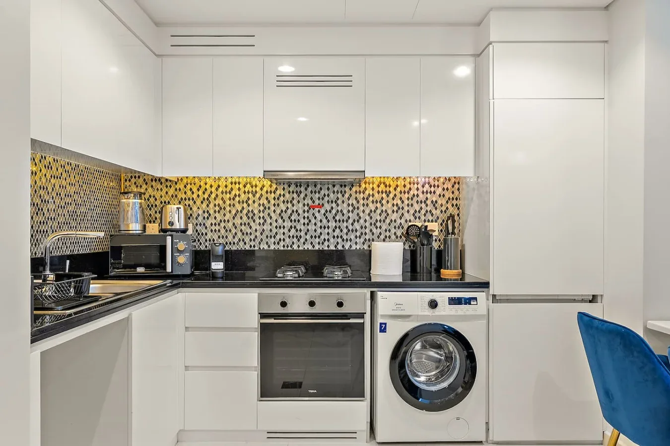 Una cocina blanca y luminosa con una lavadora bajo la encimera.