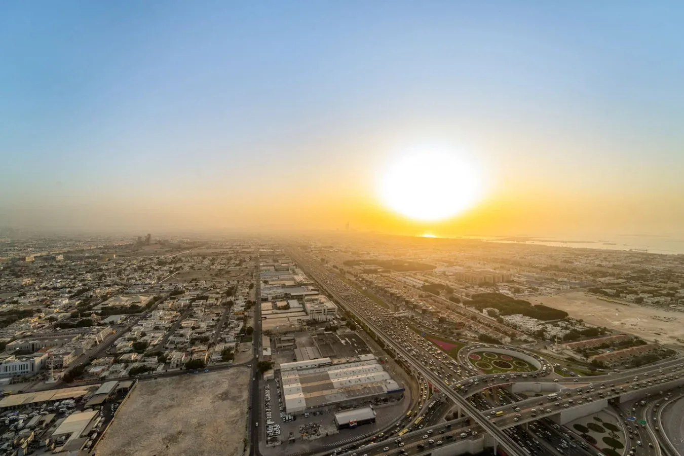 Vista aérea de una ciudad al atardecer, con carreteras que se extienden hacia el horizonte.