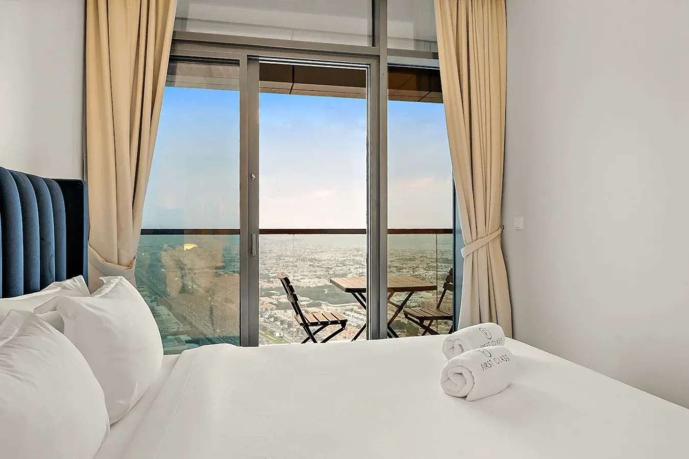 Un dormitorio con una cama junto a puertas de vidrio que dan a un balcón con vista al mar.
