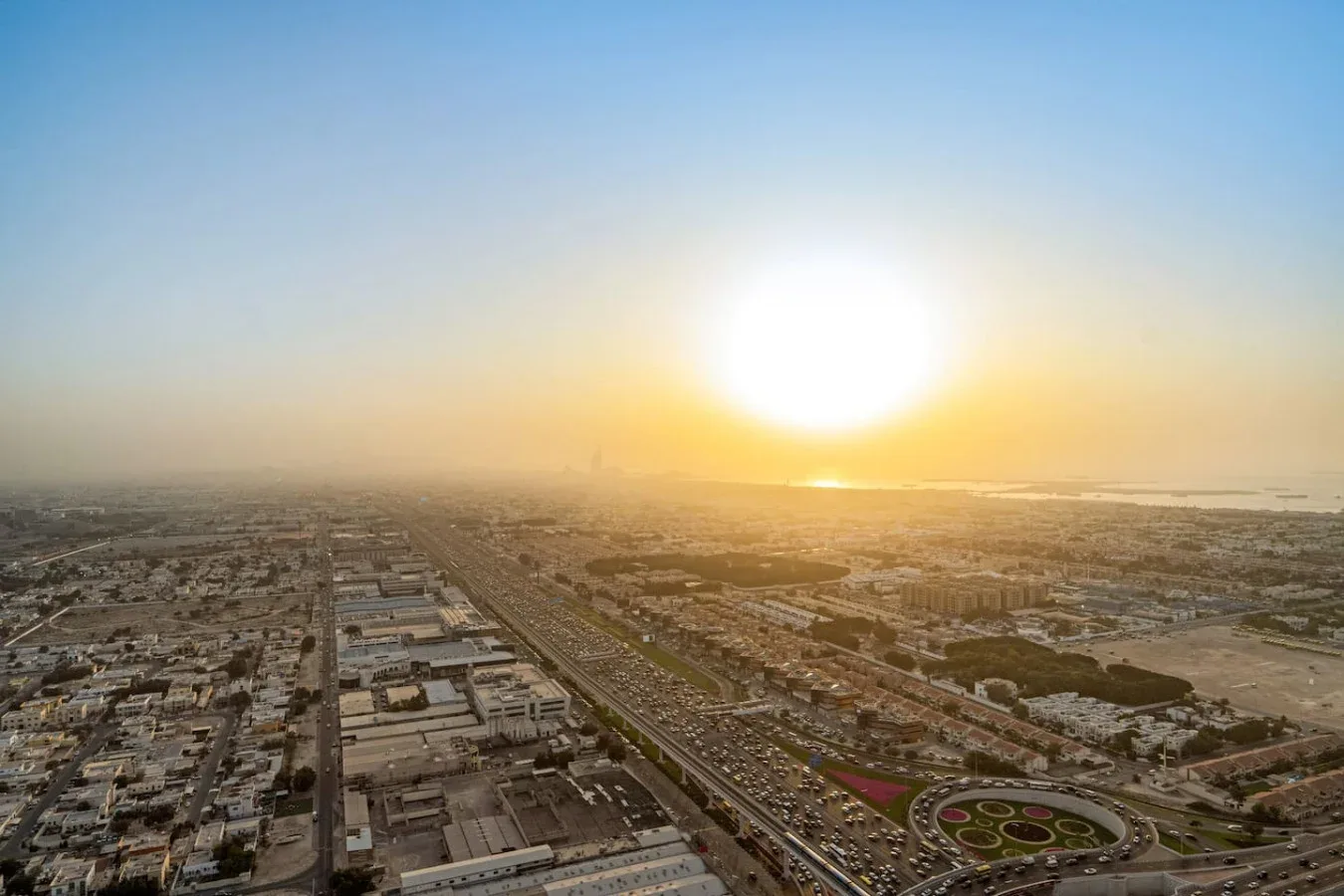 Vista aérea de una ciudad extensa al atardecer, con calles y edificios hasta el horizonte.