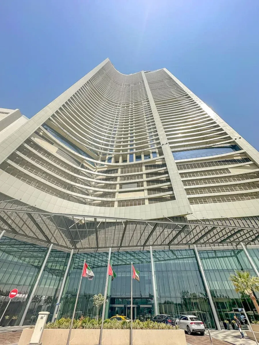 Un edificio moderno y alto se eleva sobre una entrada con fachada de vidrio.