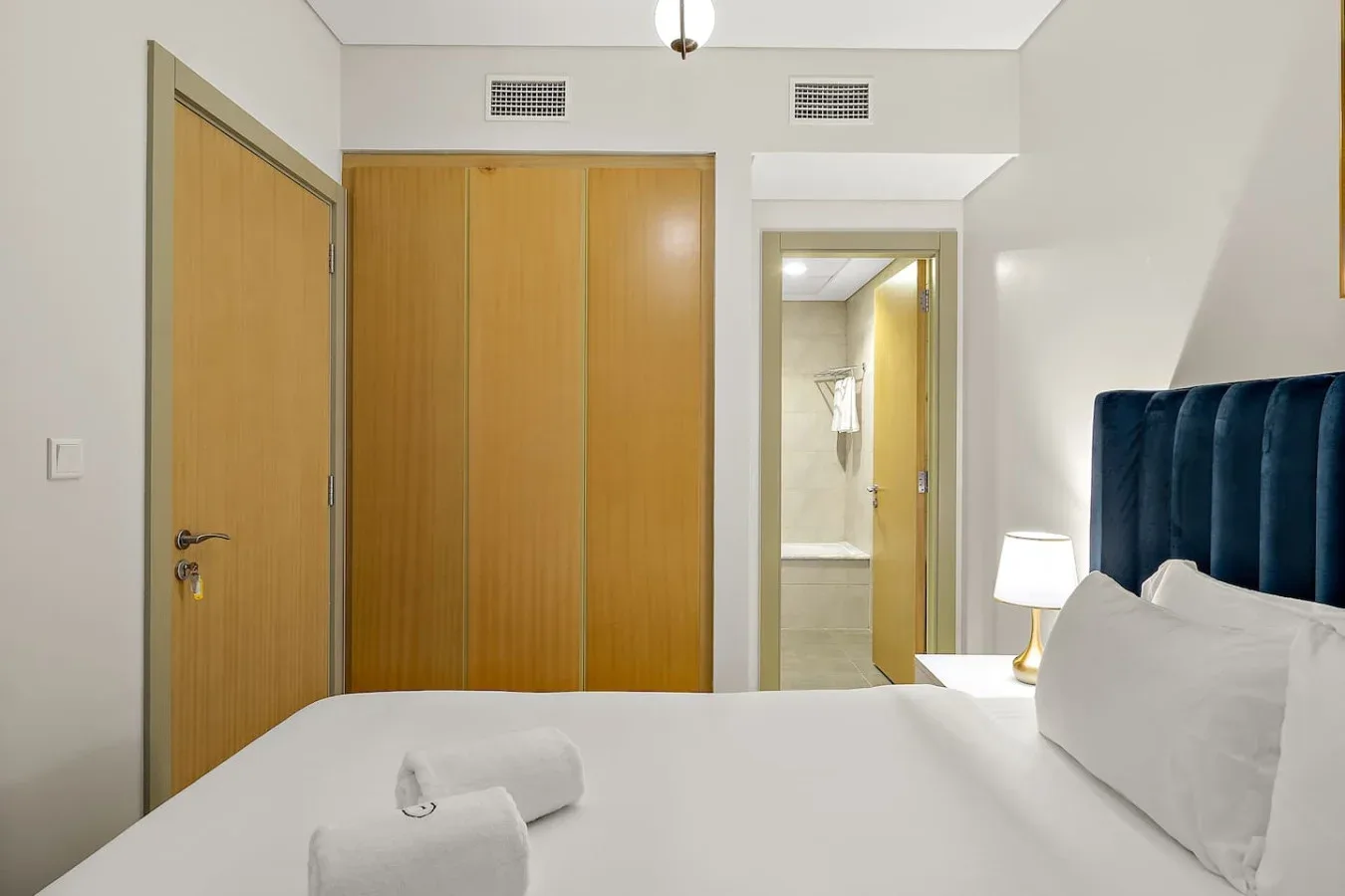 Un dormitorio con una cama ordenada y un baño visible a través de la puerta.