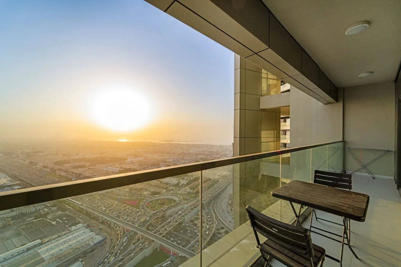 Una zona de estar en un balcón ofrece vistas de la ciudad al atardecer.