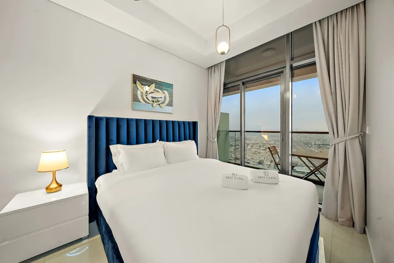 Un dormitorio con una cama junto a grandes ventanales con vistas a la ciudad.