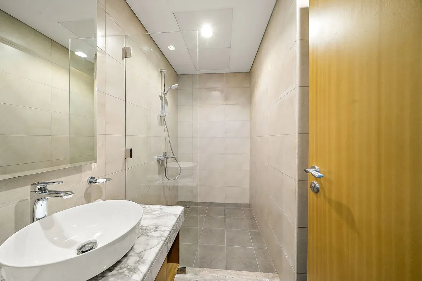 Un baño alicatado con lavabo, encimera y ducha.