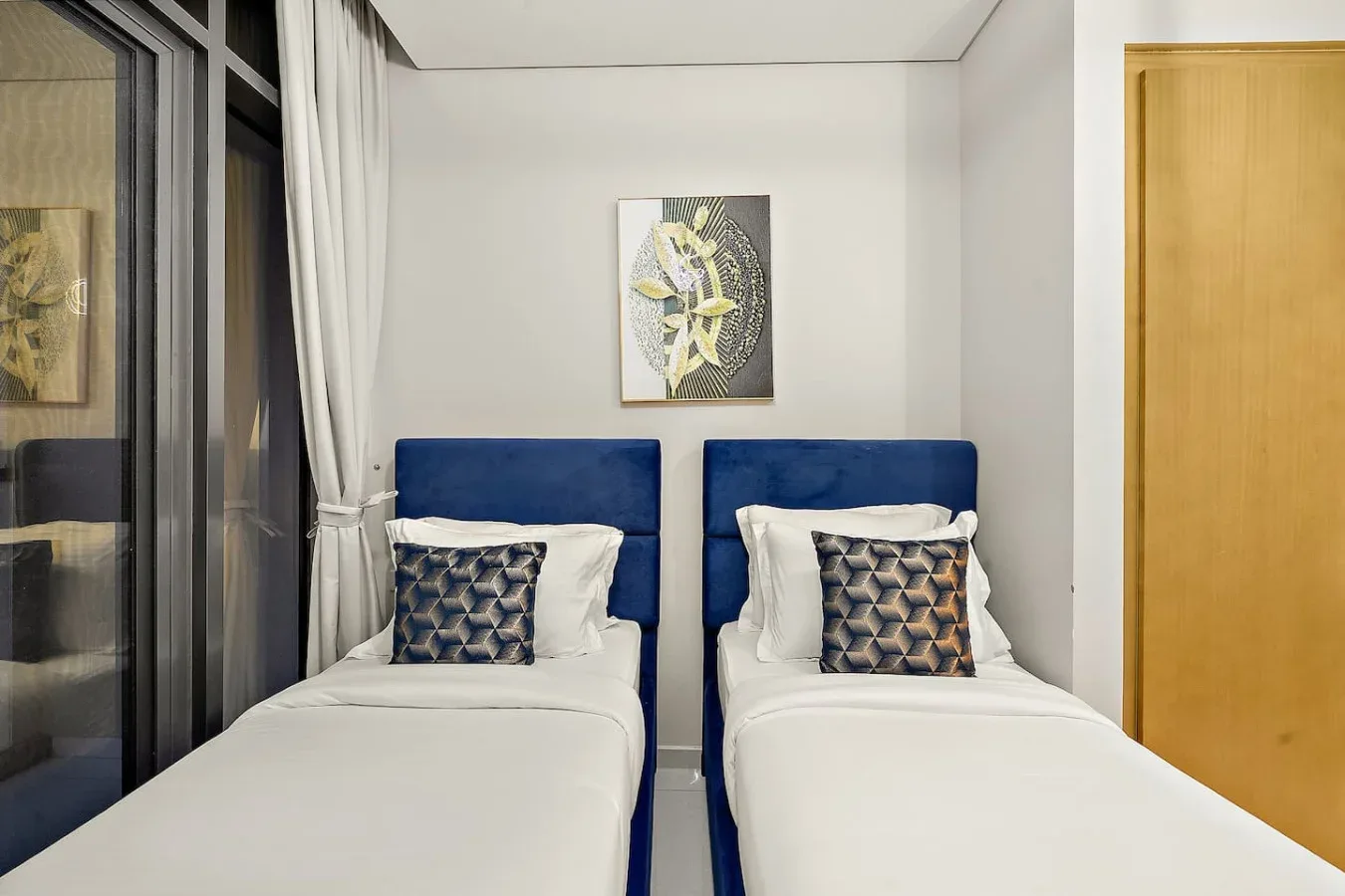 Un dormitorio con dos camas individuales bajo una obra de arte en la pared.