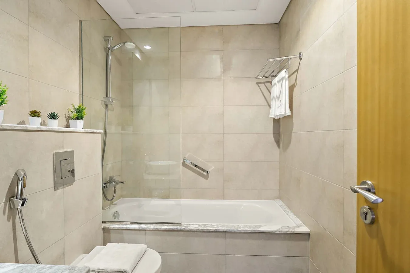 Un baño alicatado con bañera, accesorios de ducha y un toallero.