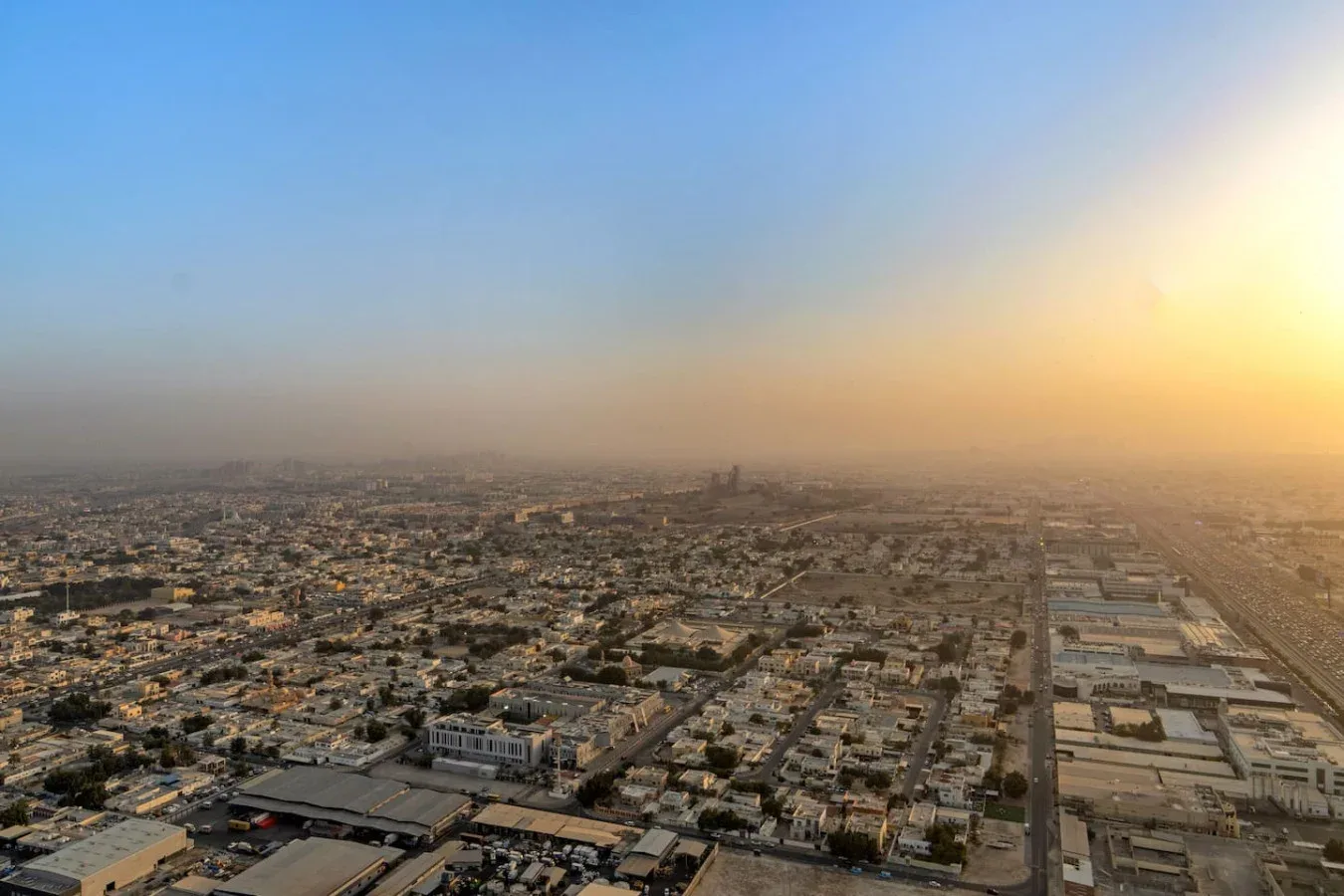 Vista aérea de una ciudad extensa al atardecer bajo un cielo brumoso.