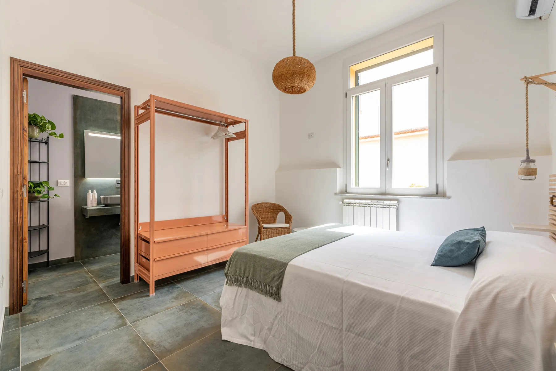 Un dormitorio luminoso con una cama, un armario de madera y una ventana amplia.