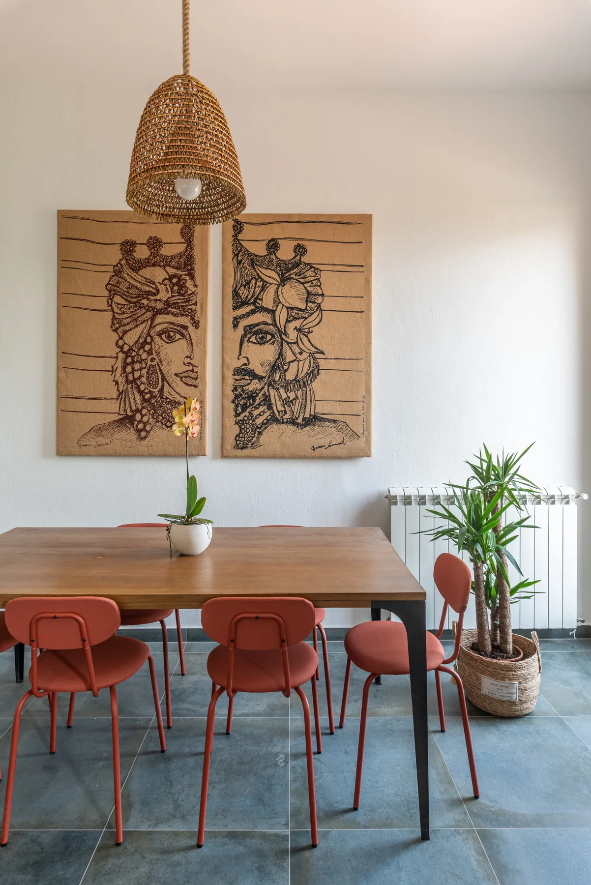 Un comedor con una mesa de madera, asientos rojos y un cuadro enmarcado.