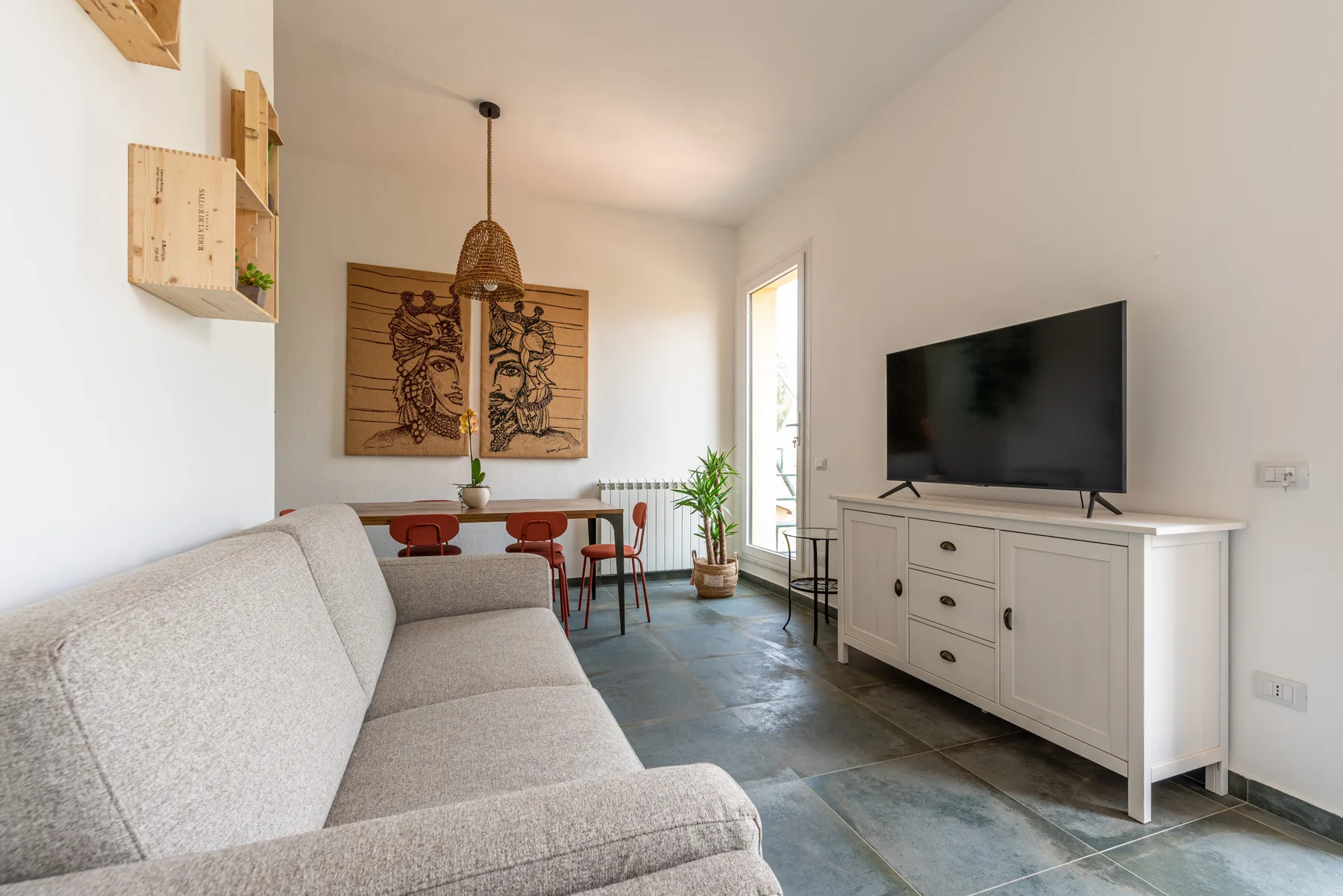 A bright living room with a sofa, television, and dining table.