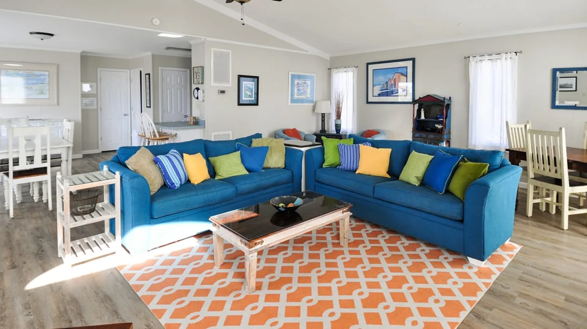 A bright living room with blue sectional seating around a patterned rug.