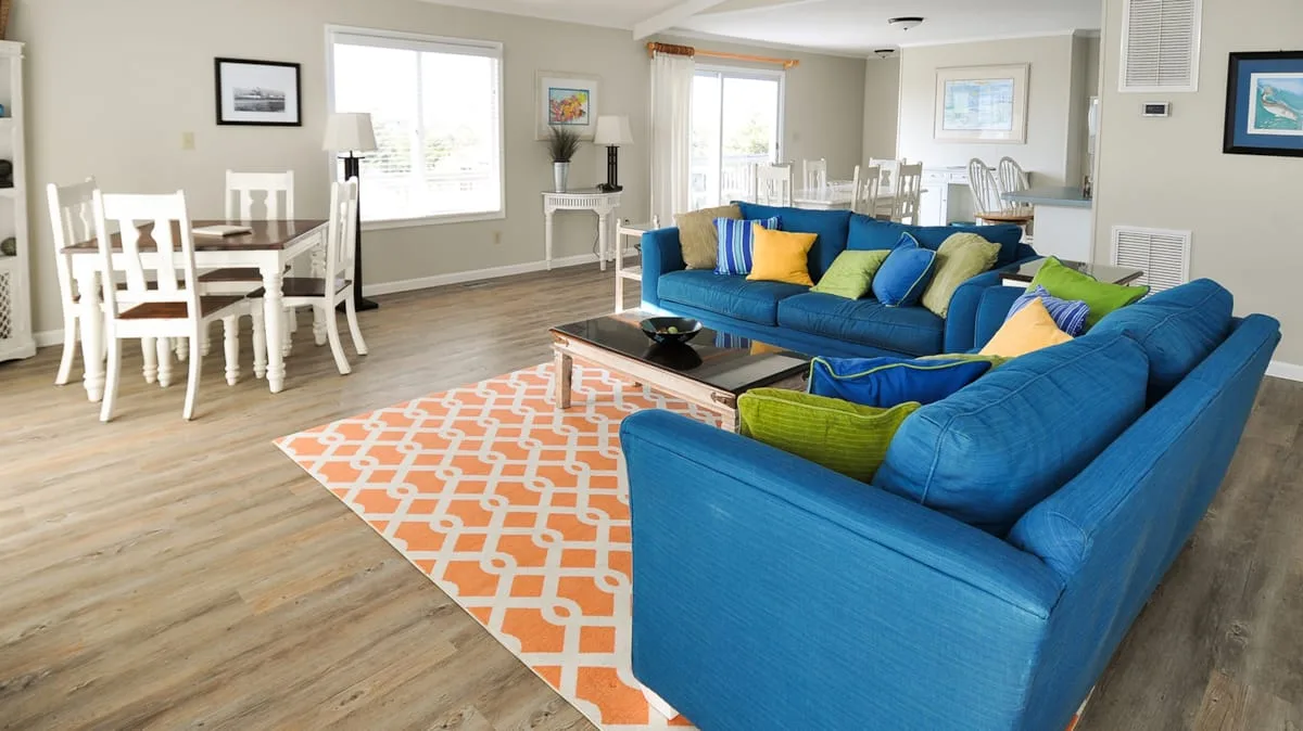 A bright living and dining area with blue seating and a white dining table.