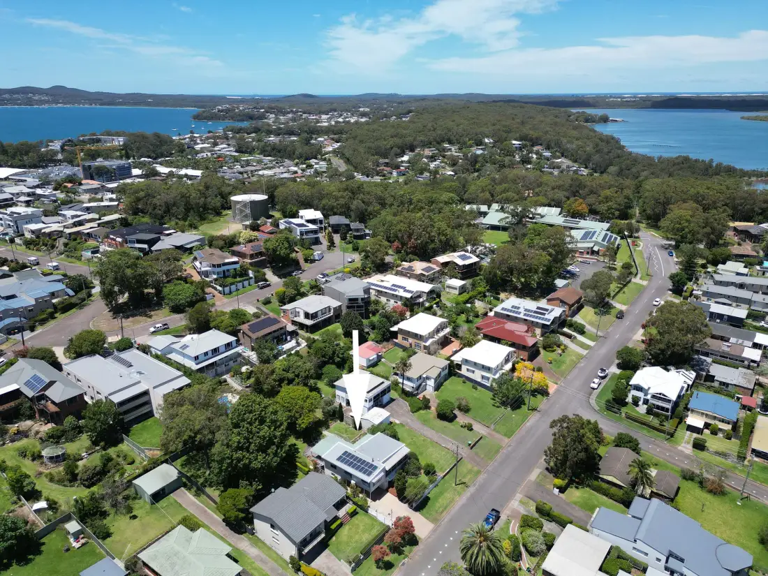 Aerial view of a leafy residential neighborhood beside the water.
