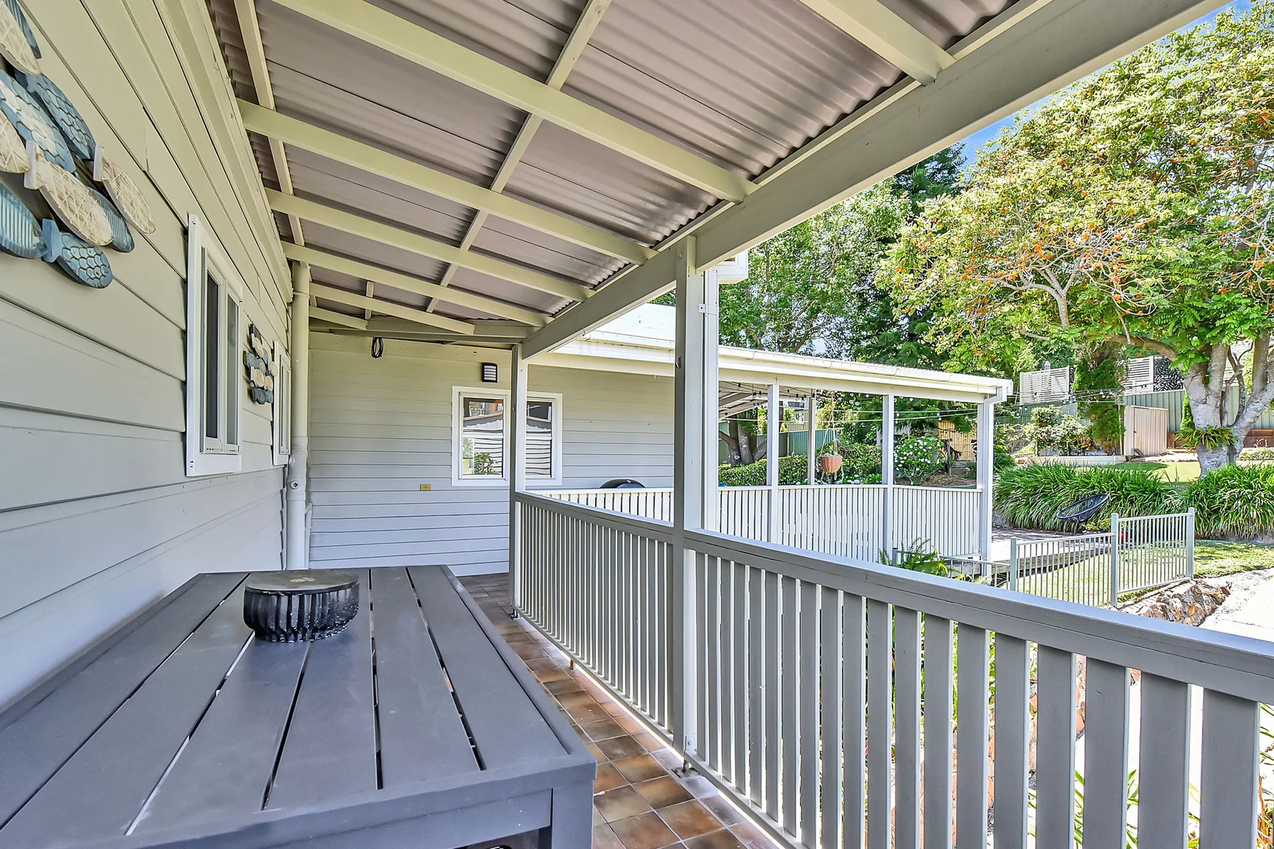A covered outdoor deck with a railing and a table.