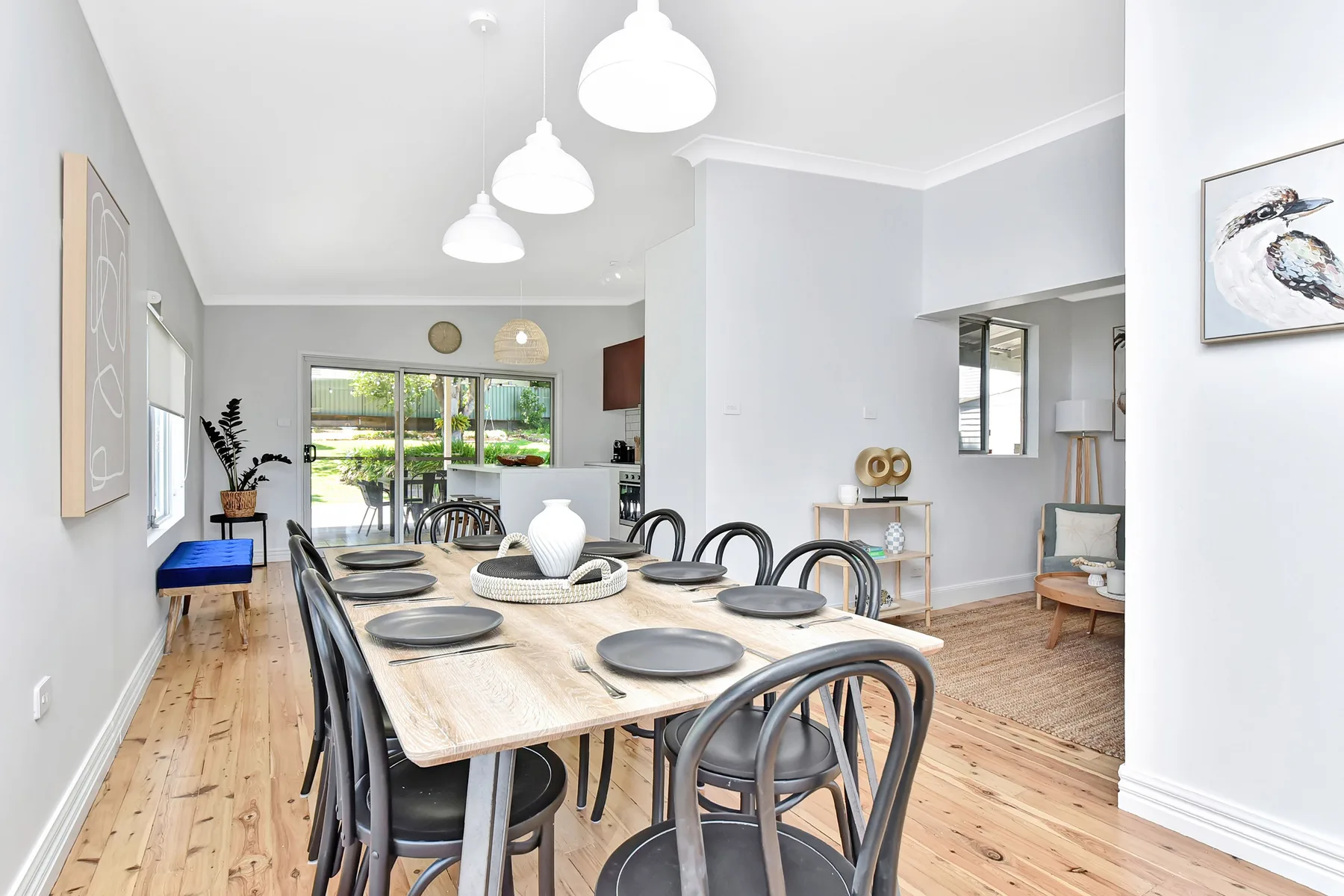 A bright dining area with a long table set with plates and chairs.