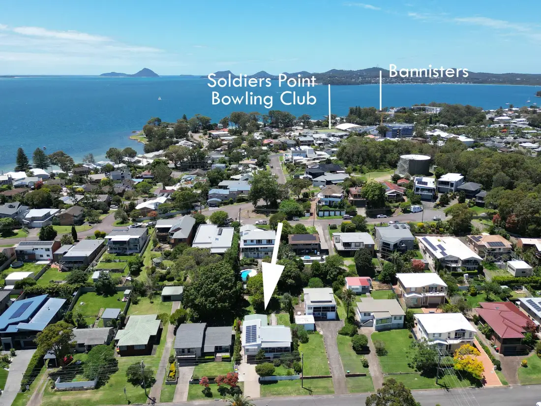 Aerial view of a coastal neighborhood with homes and the sea beyond.