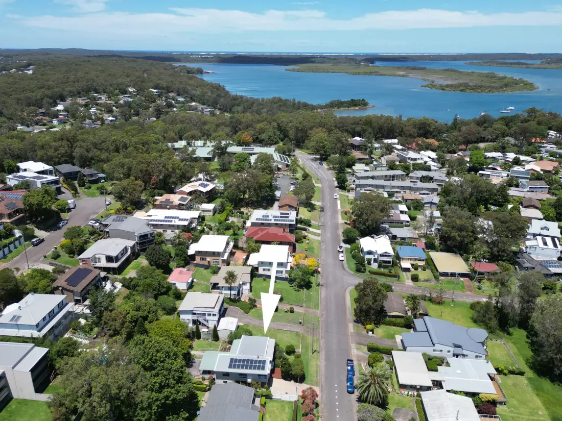 Aerial view of a residential neighborhood beside a broad coastal inlet.