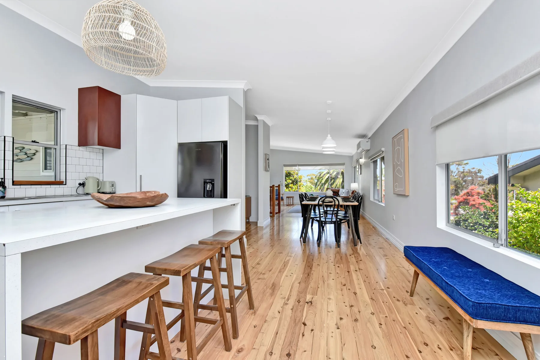 A bright open-plan kitchen and dining area with a long wooden table.