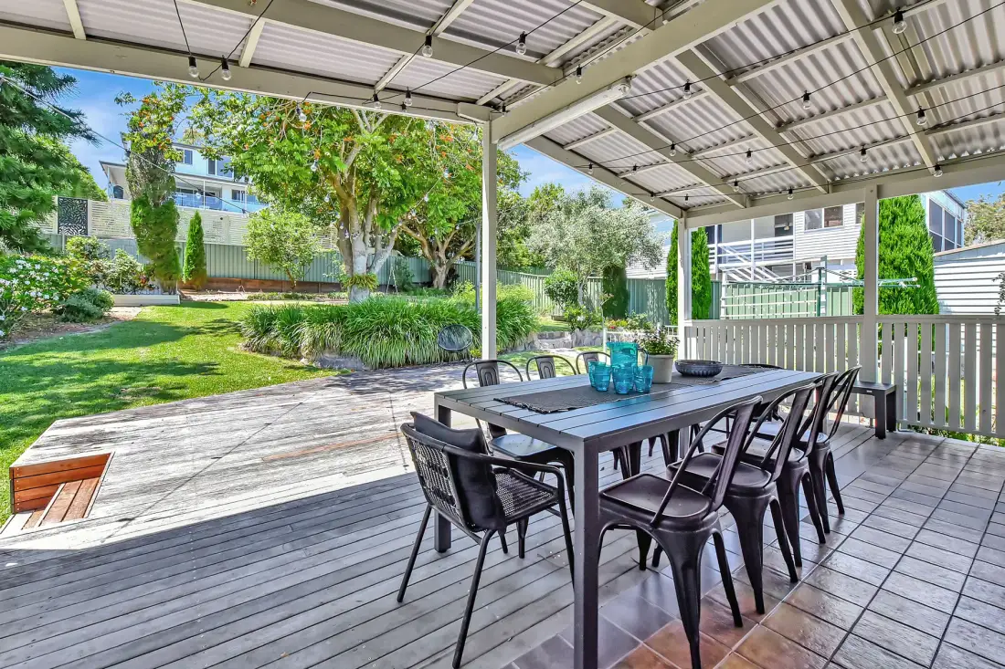A covered outdoor dining area opens onto a landscaped garden.