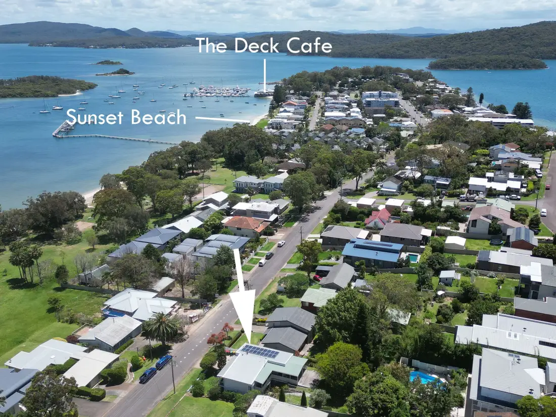 Aerial view of a coastal neighborhood beside a bay, with beaches and boats.