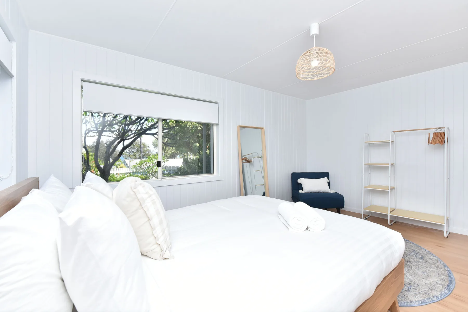 A bright bedroom with a large bed and a window overlooking trees.