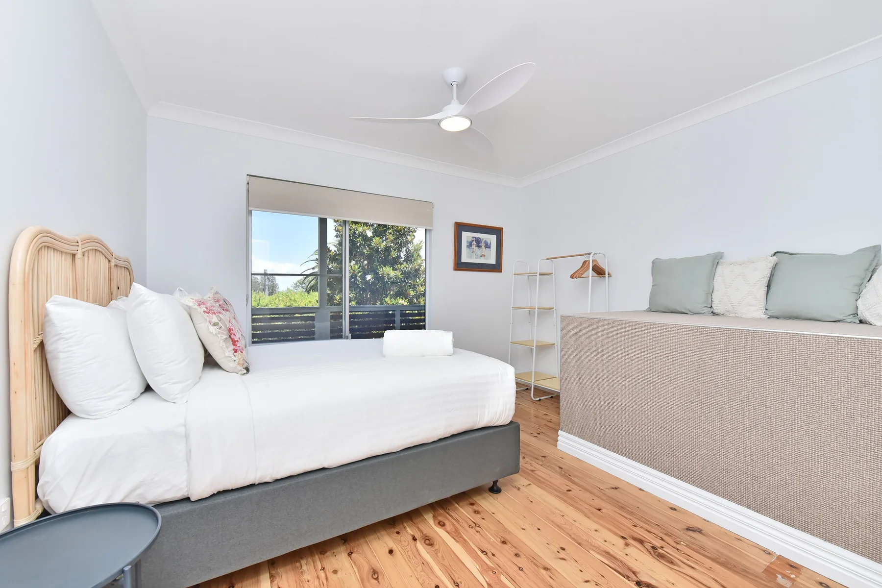 A bright bedroom with a bed, a window, and a ceiling fan.