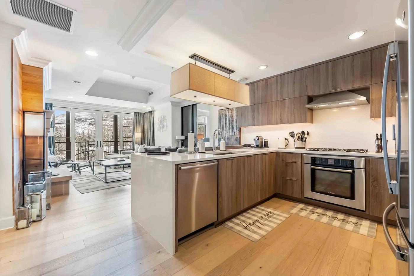 Una cocina moderna con gabinetes de madera e isla amplia se abre a una luminosa sala de estar.