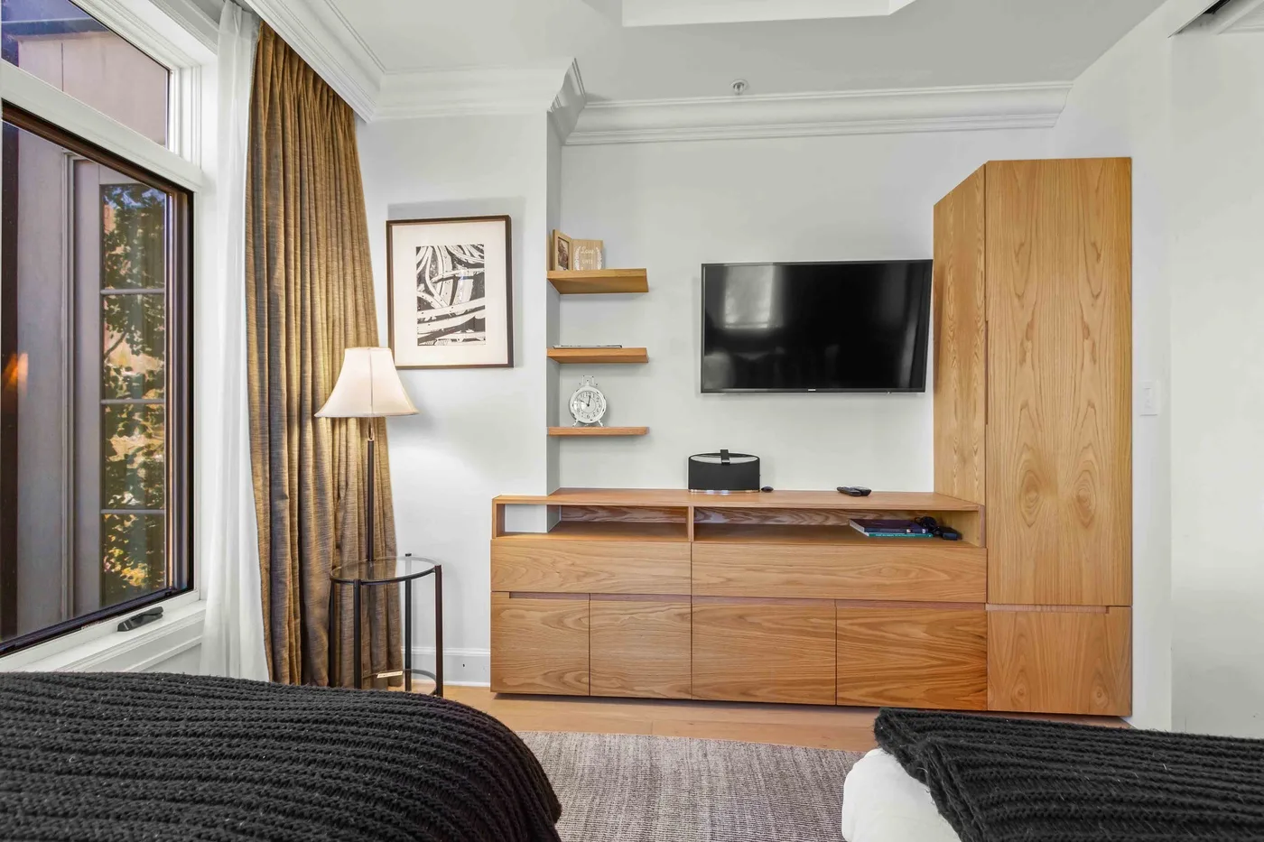 Un dormitorio con un televisor sobre un mueble de madera.