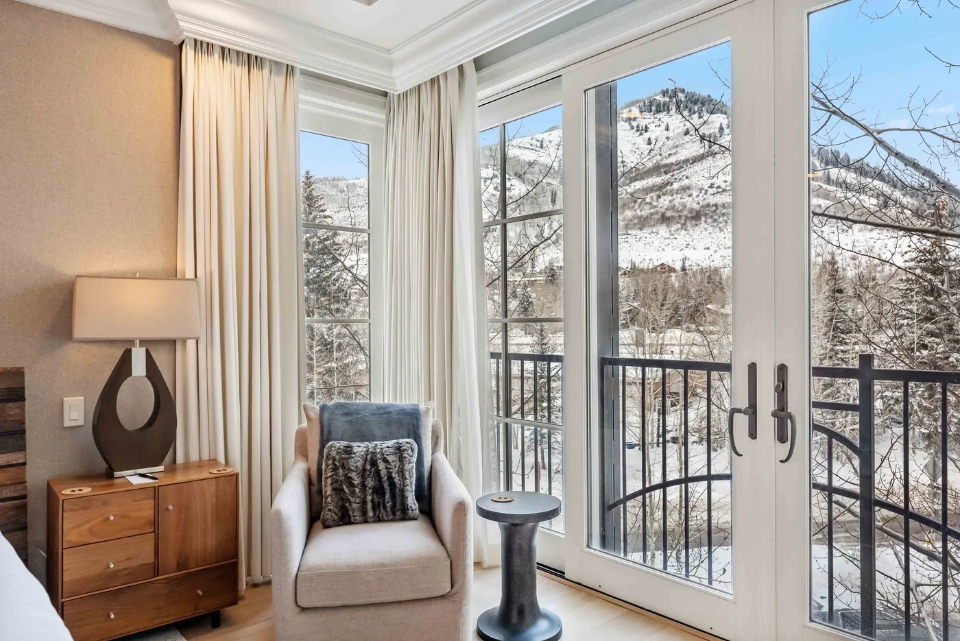 Una zona de estar luminosa con grandes ventanas que dan a un paisaje montañoso nevado.