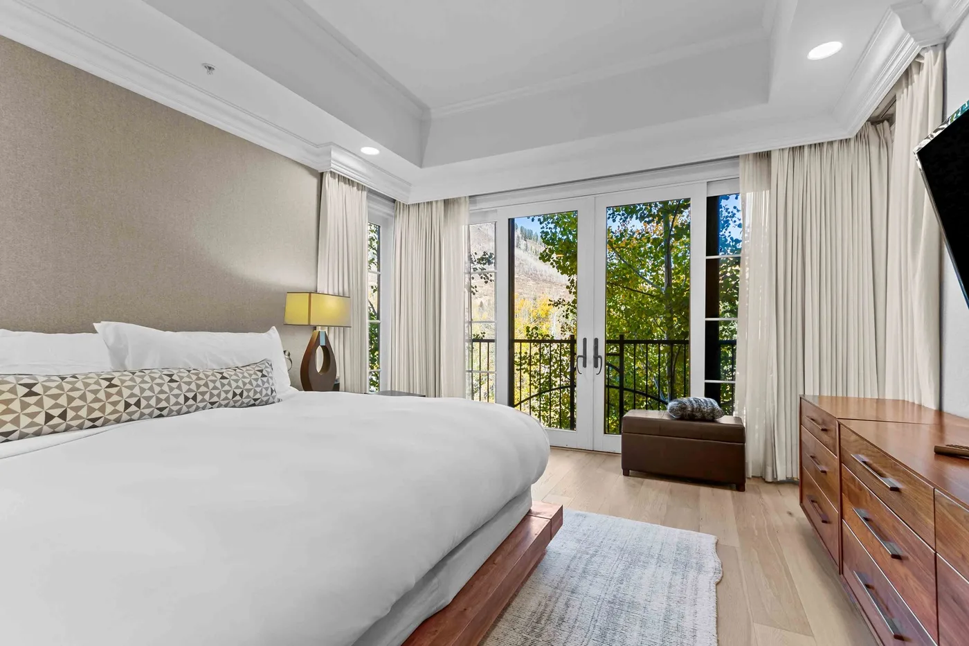 Un dormitorio luminoso con una cama grande y puertas de vidrio que dan a un balcón.