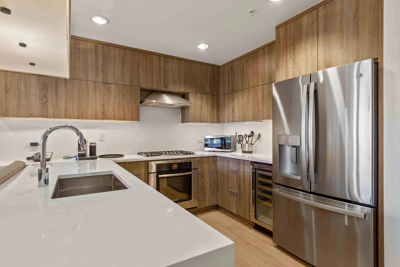 Una cocina moderna con gabinetes de madera, una isla grande y electrodomésticos de acero inoxidable.