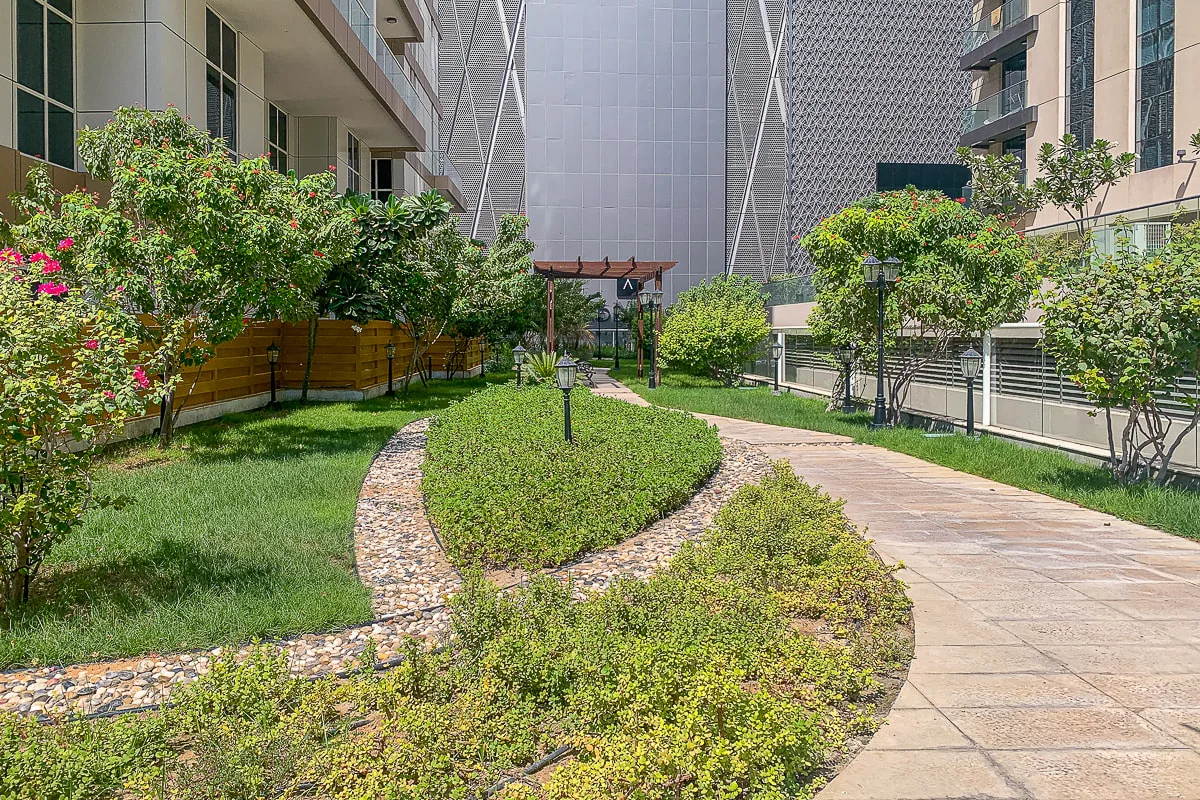 Un sendero en un patio ajardinado serpentea entre parterres y edificios.