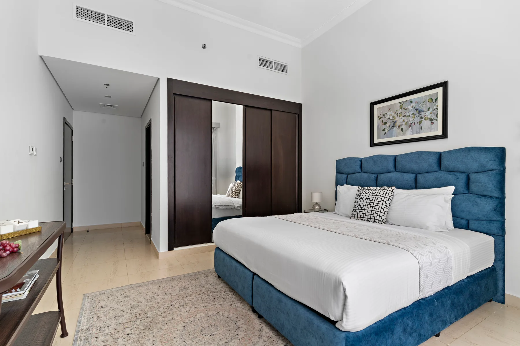 Dormitorio con una cama tapizada azul y un cuadro enmarcado encima.
