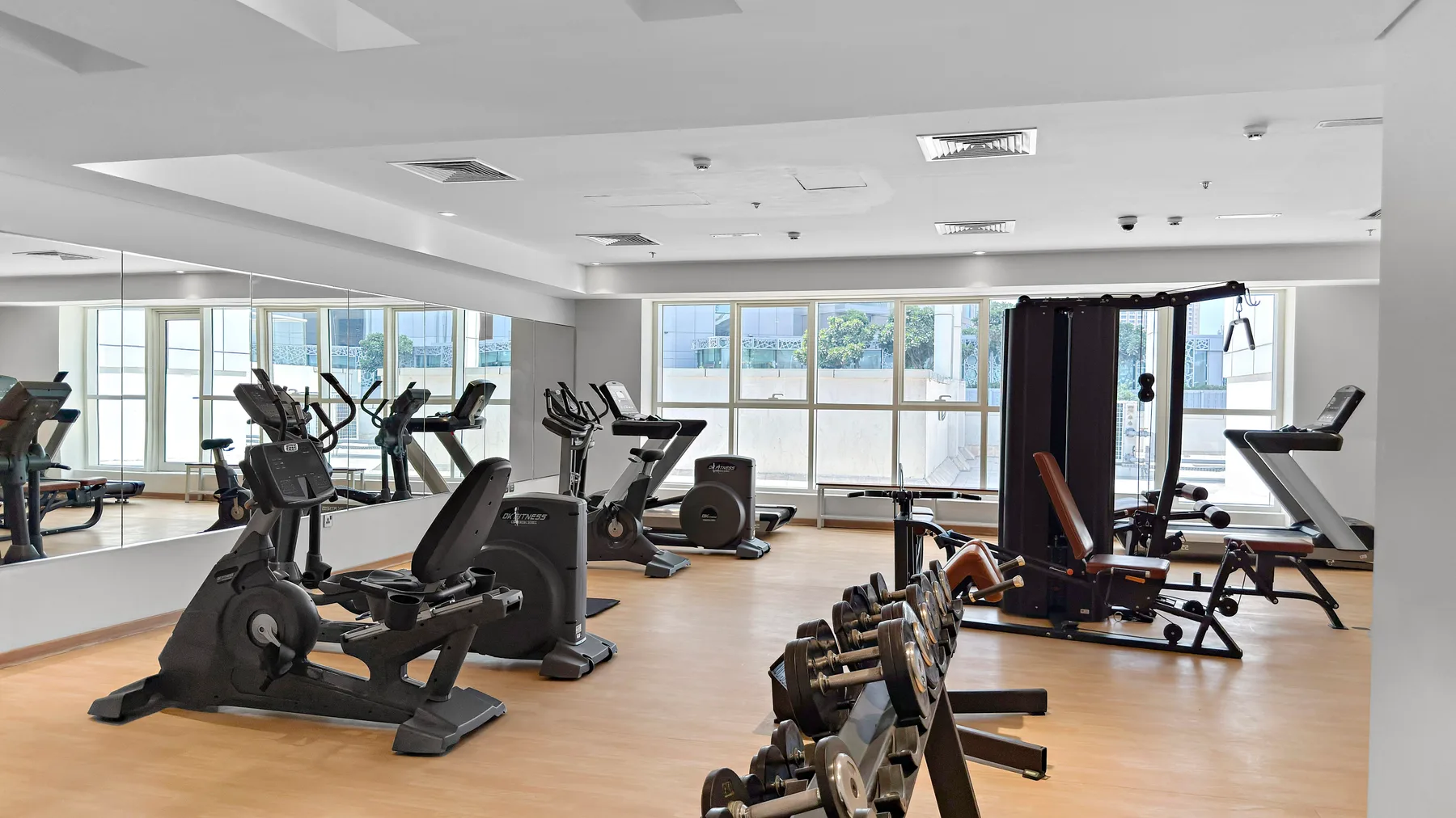 Un gimnasio luminoso con máquinas de ejercicio, pesas y grandes ventanales.